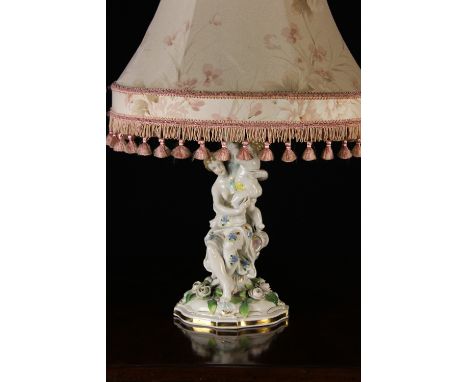 A Continental Porcelain Figural Table Lamp modelled in the form of a nymph and cherub sat on a serpentine base encrusted with