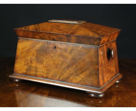 A Large 19th Century Flame Mahogany Tea Caddy of sarcophagus form. The hinged lid opening to reveal three lidded compartments