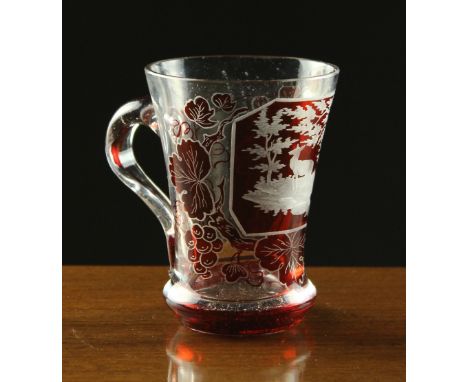 A Small Bohemian Glass Mug. The flared sides decorated with ruby flashed vine scrolling around an engraved panel depicting st