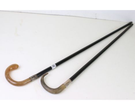 Two vintage ebonised walking sticks with horn handles and silver collars. 