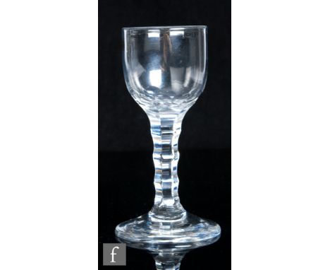 An 18th Century drinking glass, circa 1785, the ovoid bowl with basal cutting above a ladder cut facet stem, raised to a coni