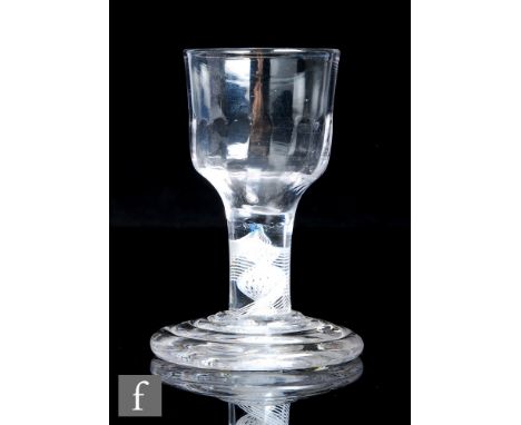 An 18th Century drinking glass, circa 1765, the ogee form bowl with basal fluting above an opaque stem with a fifteen ply spi