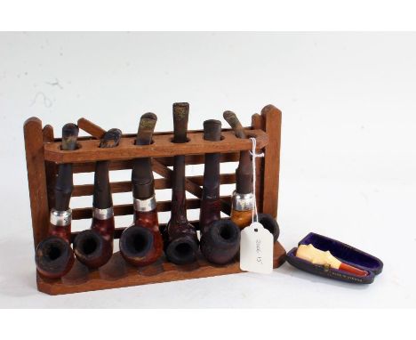 Collection of six pipes on stand, four with sterling silver mounts, the stand in the form of a gate, 23.5cm wide, together wi