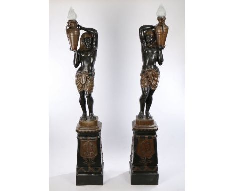 Pair of Egyptian revival metal torchere's, the figural lamps with an Egyptian figure holding a flaming lamp above a tapered s