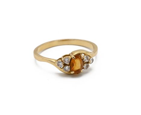 An 18ct yellow gold topaz and white stone ring, the oval cut orange topaz flanked by six round cut white stones, ring size O1