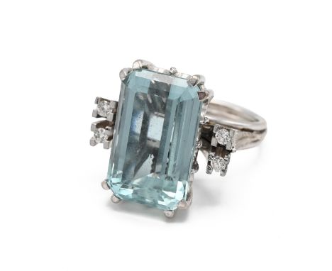 A 15ct white gold aquamarine and diamond cocktail ring, the step cut aquamarine approximately 17mm x 11mm, flanked by four ro