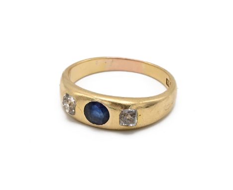 An 18ct yellow gold sapphire and diamond three stone ring, set with an oval cut sapphire, flanked by two old cut diamonds, ri
