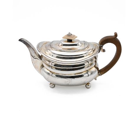 A George III silver teapot, standing on four bun feet and having a curved wooden handle, London 1820, makers mark worn, 626 g