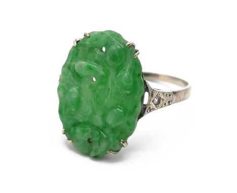 An Art Deco style 9ct white gold jade and diamond dress ring, set with an oval carved and pierced jade panel, approximately 1