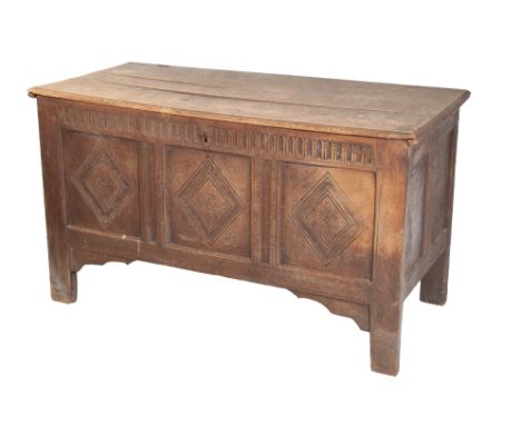 A 17TH CENTURY OAK COFFER with later elements, the hinge top above a panel front, carved with lozenges on block feet, 69cm hi