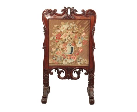 A WILLIAM IV MAHOGANY FIRESCREEN early 19th century, the carved and shaped cresting rail over a needle work panel, with pierc