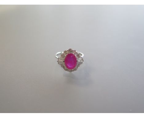 An 18ct white gold ring set with an oval ruby, surrounded by a halo of round brilliant cut and tapered baguette diamonds - Ru