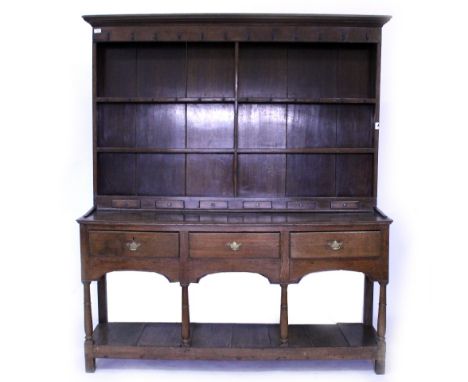 A GEORGE III AND LATER OAK DRESSER with plate rack above containing six spice drawers, the base with three drawers over a pot