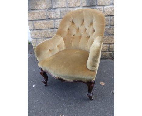 A Victorian velvet and button back upholstered armchair, raised upon walnut cabriole front supports to castors.