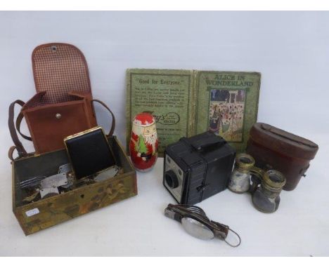 A tin of mixed collectables including a cased pair of binoculars, a Brownie camera, a Father Christmas Russian doll, a Ronson