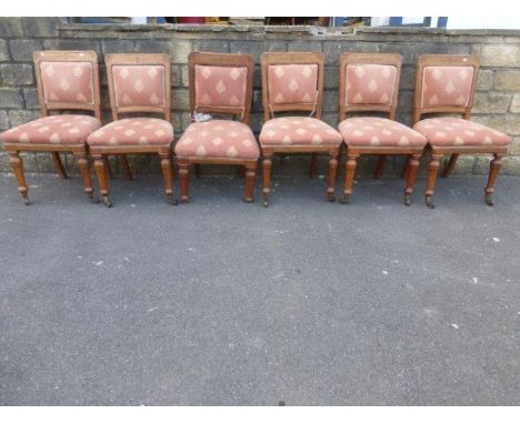 A set of six late Victorian light oak dining chairs with padded backs and over-stuffed seats, raised on turned tapering suppo