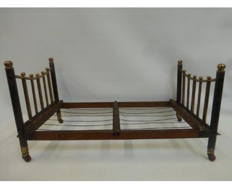A Victorian brass and oak doll's bed terminating in brass caps and porcelain castors.