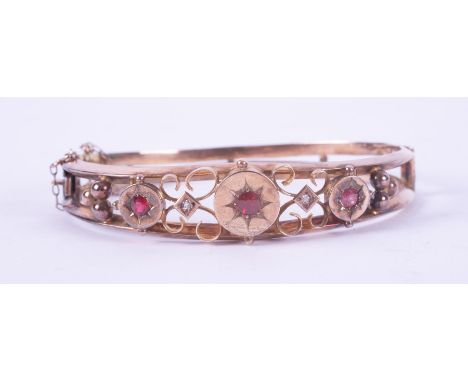A 9ct yellow gold antique ornately designed bangle set with three round cut red stones &amp; two small round cut white stones