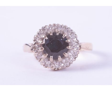 An 18ct yellow gold cluster ring set with a central round cut dark blue sapphire, approx. 1.05 carats, surrounded by small ro