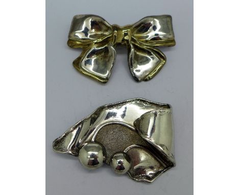 A .925 silver brooch in the form of a bow and an Arts and Crafts style white metal brooch, both 7cm wide, weight 64g