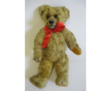A Chad Valley teddy, 1920s, with swivel joints, sewn nose, amber eyes, felt pads, orange plush, button to ear and label to fo