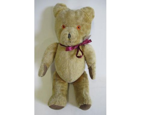 A vintage teddy bear, with sewn nose, amber plastic eyes, felt pads and swivel joints, 21 1/4" long, together with a straw ha
