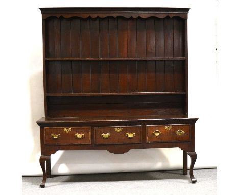 George III oak dresser, delft rack with cavetto cornice, shaped frieze, two fixed shelves with later panelled back, the base 