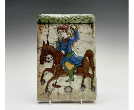 A Persian pottery tile, 19th century, depicting a figure on horseback, 22.5 x 15.5cm.