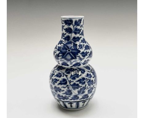 A Chinese porcelain blue and white double gourd vase, 19th century, with Kangxi four character mark, with lea vines and large