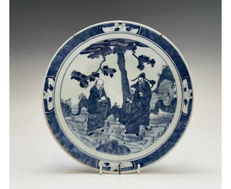 A Chinese porcelain blue and white charger, 19th century, depicting three figures beneath a tree, within a trellis and prunus