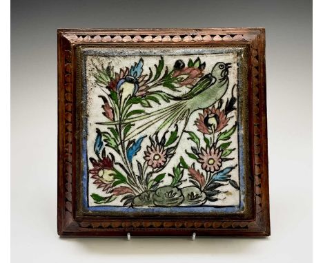 A Persian pottery tile, mounted in an oak stand, on turned feet, size of tile 19 x 18.5cm.