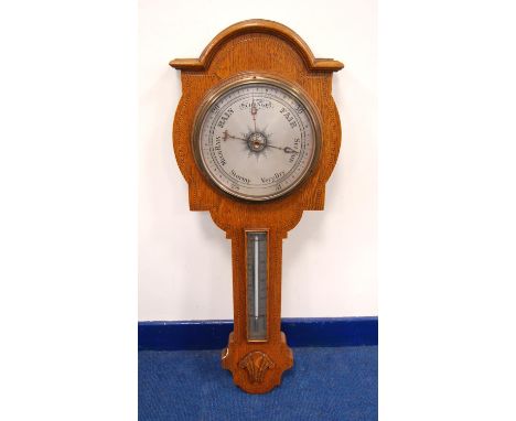 Late 19th century or early 20th century oak barometer, the moulded arched pediment over brushed metal face, tapering trunk, t