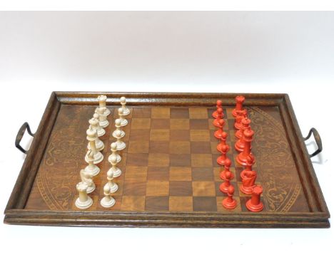 A late 19th century carved bone natural and stained chess set, and a chess board/tray