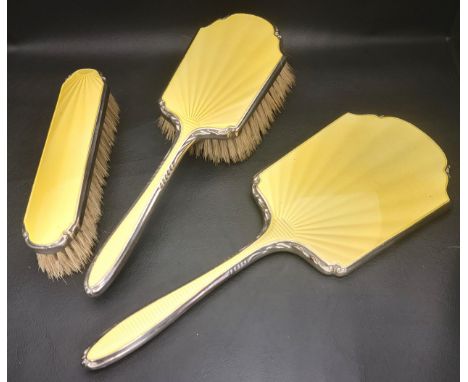 THREE PIECE ENAMEL DECORATED SILVER DRESSING TABLE SETcomprising two brushes and a hand mirror, all with yellow guilloche ena