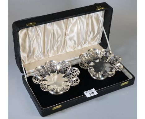 Cased pair of silver sweet meat dishes with scalloped edges and pierced decoration, both standing on circular pedestal bases.