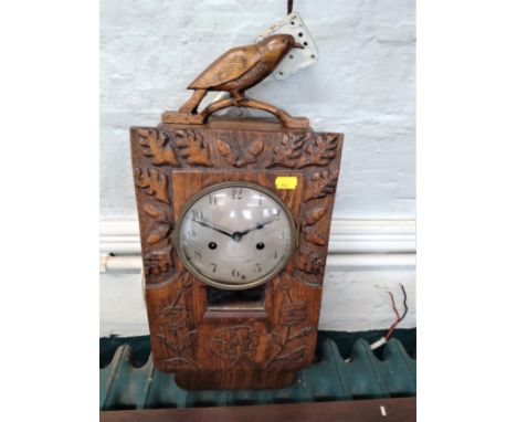 A carved Hardwood Wall Clock. The silvered dial with Arabic numerals. Surmounted by a bird. 