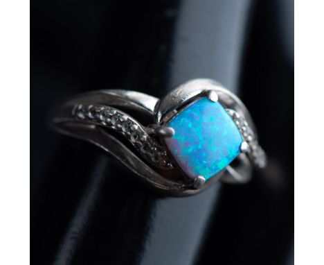 This ring is sterling silver set with a small opal in the center and round cubic zirconia stones. Inside of the band is marke