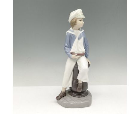 Glossy figure in sailor clothing holding his yacht. Lladro backstamp. This item has its original box: 10"L x 5.25"W x 5"H. Ar