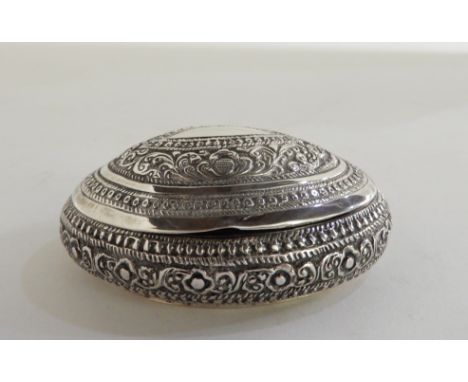 An Eastern silver snuff box, unknown marks of oval form, the hinged cover and body with embossed decoration, the base engrave