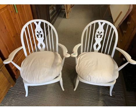 A pair of white painted Ercol chairs with open arms and stick backs, with white seat cuchions