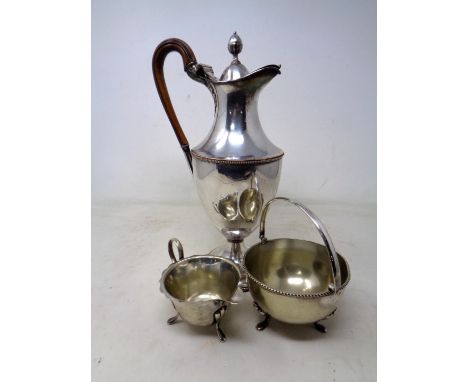 A silver plated claret jug with acorn finial together with a further plated milk jug and sugar basin.