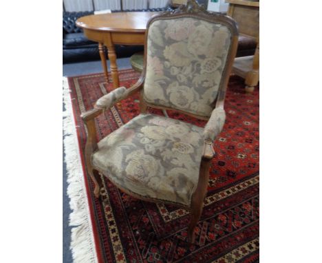 An antique French walnut armchair upholstered in tapestry fabric.