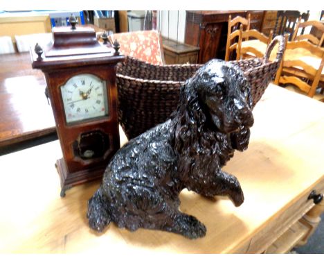 A wicker twin handle basket together with a dog ornament and a mantel clock.