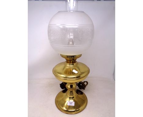 A brass table lamp in the form of an oil lamp with etched glass shade.