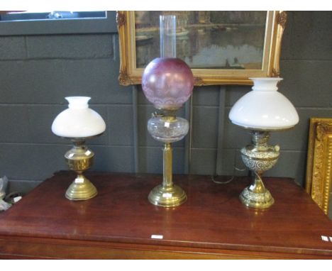 A 19th century brass oil lamp with cut glass resevoir and etched ruby glass globe, together with two brass oil lamps (3)  