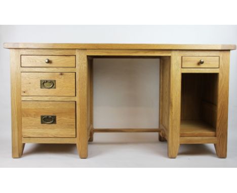A modern light oak desk, the central knee hole flanked by a single drawer above a shelved interior and a set of three graduat