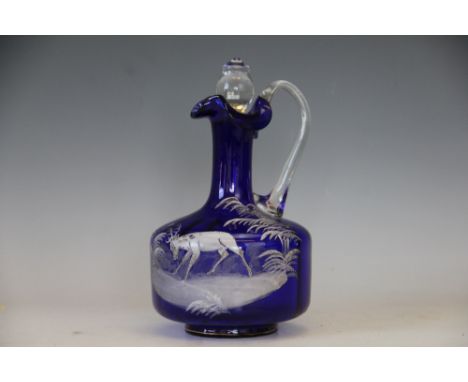 A Mary Gregory style ewer, the blue glass decanter decorated in white depicting a Stag amongst a rural landscape, associated 