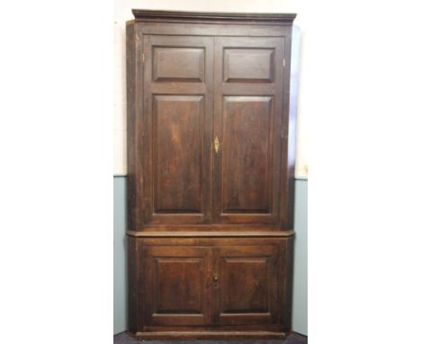 A George III stained pine full height corner cupboard, with two panelled doors above two smaller panelled doors enclosing a s