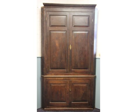 A George III stained pine full height corner cupboard, with two panelled doors above two smaller panelled doors enclosing a s