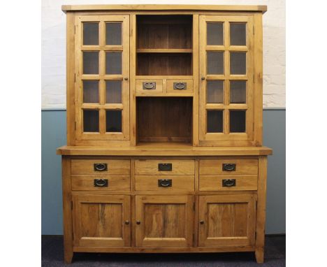 A modern light oak kitchen dresser, the top with two panelled glazed cupboard door either side a central unit, the base with 